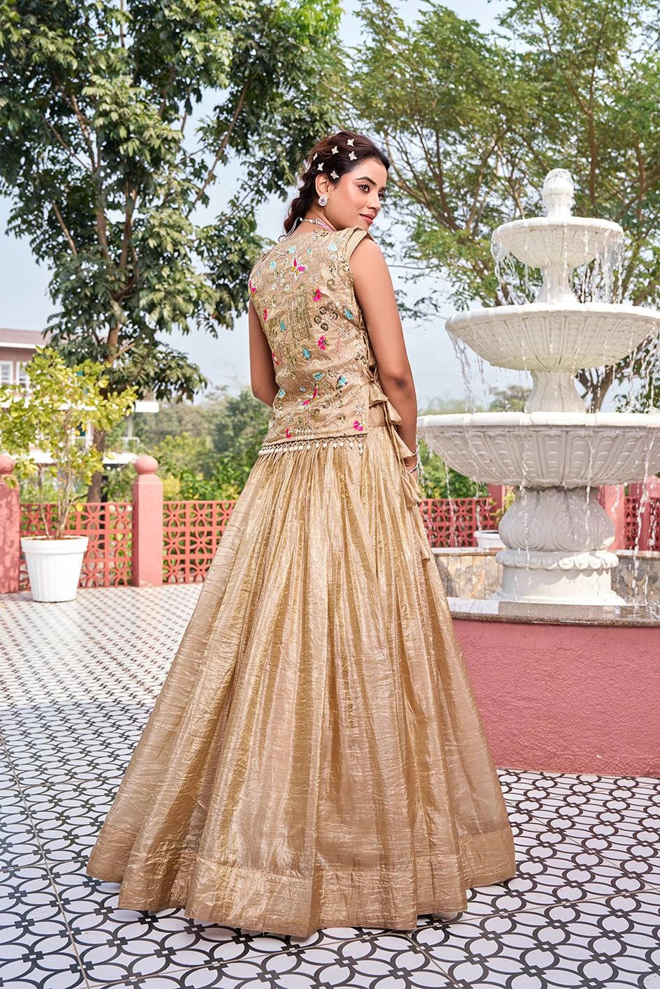 Woman in a traditional outfit standing in front of a fountain with trees in the background